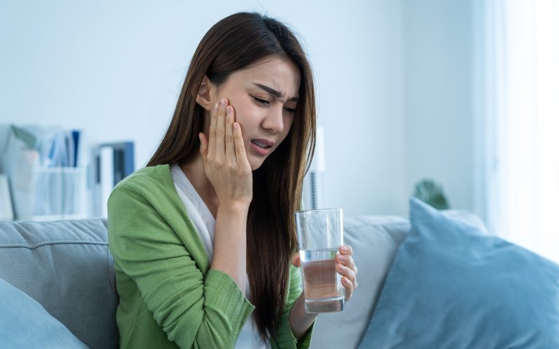 Asian beautiful woman feel terrible toothache after drink cold water.